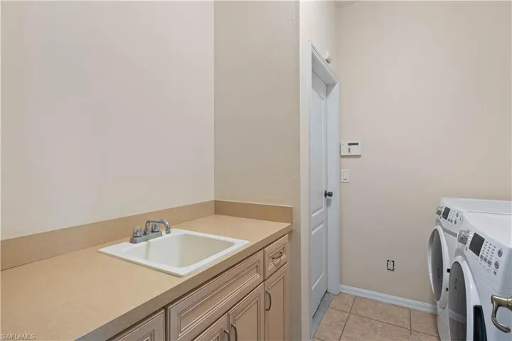 A functional laundry area with a utility sink and cabinetry for added convenience.