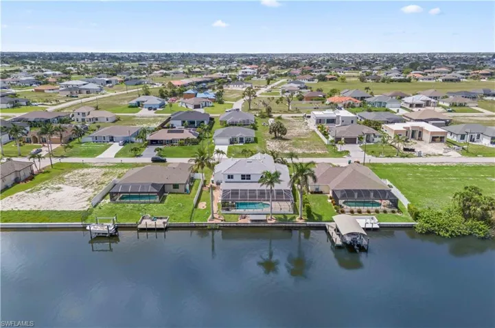 Overhead view of the lush backyard with a screened lanai, pool and spa, and direct access to the wide Gator Slough Canal. A serene, private retreat with beautiful waterfront scenery.