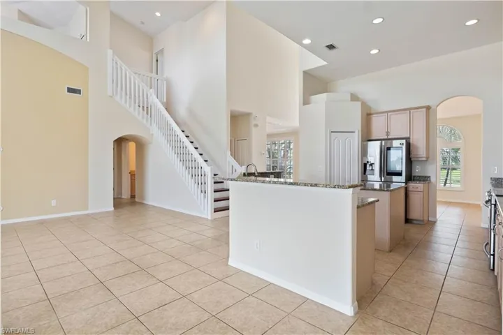 From the kitchen, enjoy a clear sightline to the elegant staircase leading upstairs, enhancing the open and airy feel of the home. This view highlights the seamless flow between cooking, dining, and living spaces.