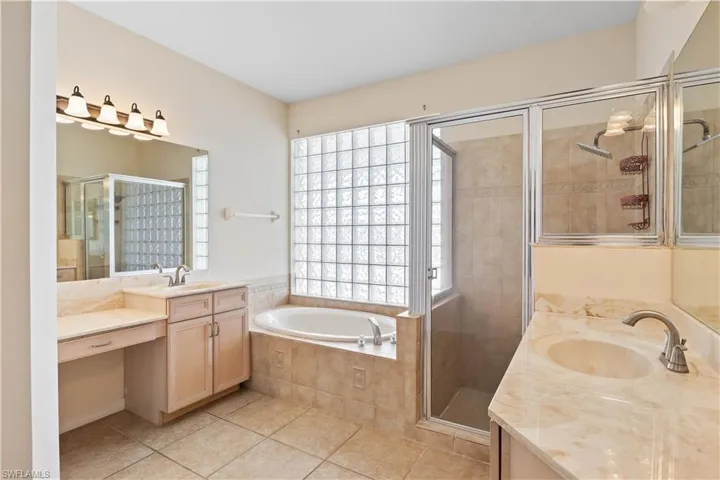 Luxurious primary bathroom featuring dual vanities, a deep soaking tub, separate glass-enclosed shower, and elegant finishes for a spa-like experience.