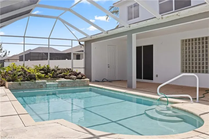 A private outdoor oasis featuring a concrete in-ground pool and spa, surrounded by a screened lanai and offering expansive canal views.