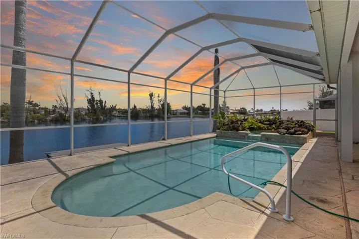 Sparkling in-ground pool and spa set within a spacious screened lanai, perfect for outdoor entertaining. Surrounded by tropical landscaping and peaceful canal views.