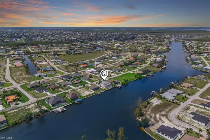 Expansive aerial shot showcasing the wide canal, nearby homes, and the peaceful waterfront neighborhood. Highlights Cape Coral’s signature canal system and relaxed coastal lifestyle.