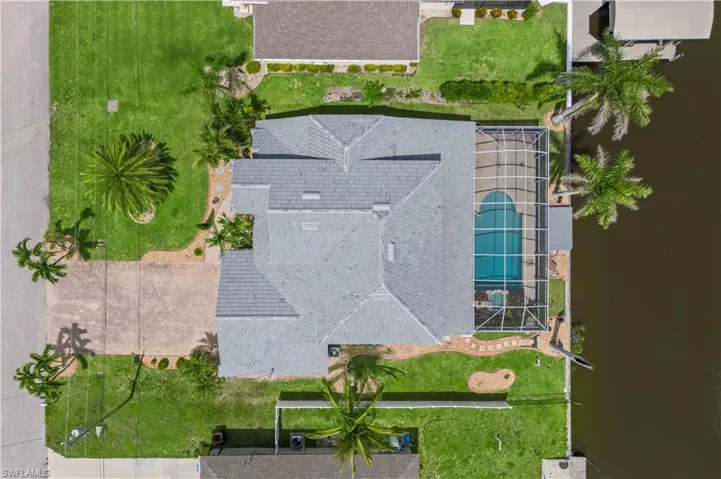 Aerial photo highlighting the full home and grounds, with the canal, dock, and surrounding neighborhood visible—offering a complete picture of the property’s setting and lifestyle potential.