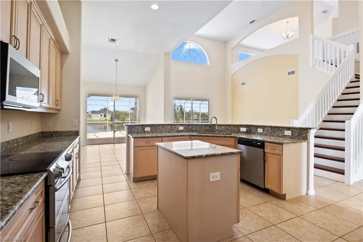 A comfortable and inviting space with tile flooring and large windows, seamlessly connecting to the kitchen and breakfast nook.
