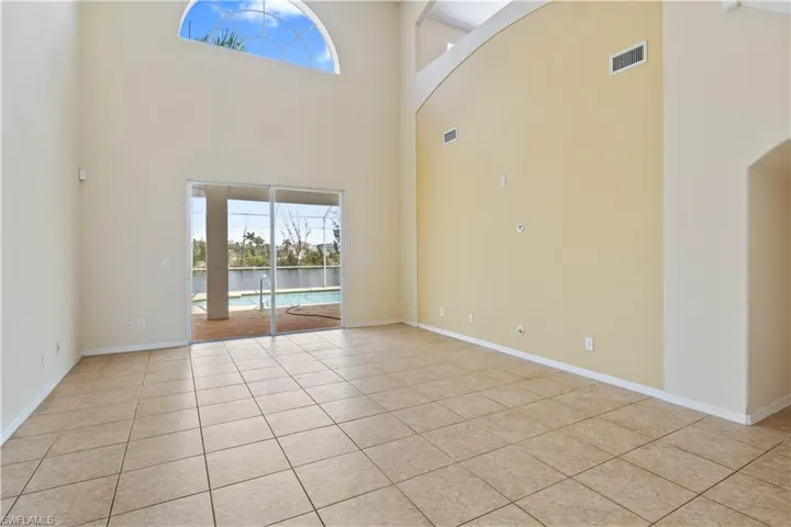 Bright living area featuring tall ceilings and large windows, offering a grand sense of space and stunning views of the outdoors.