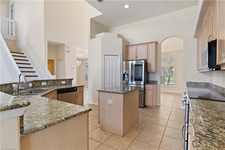 A chef's dream kitchen featuring granite countertops, stainless steel appliances, a central island, and a walk-in pantry.