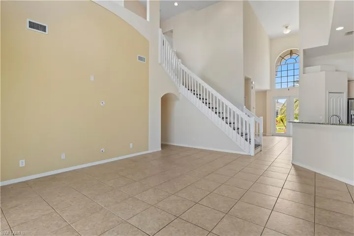 Welcoming foyer with soaring ceilings and an elegant staircase that gracefully curves upstairs. From here, the open layout flows seamlessly into the bright kitchen, creating a spacious and inviting entrance to the home.