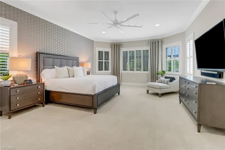 The over-sized primary bedroom overlooks the covered lanai and pool area.