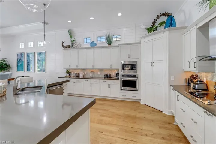 Gourmet kitchen with quartz countertops, wood floors, upscale appliances and walk-in pantry adjacent to dining room.