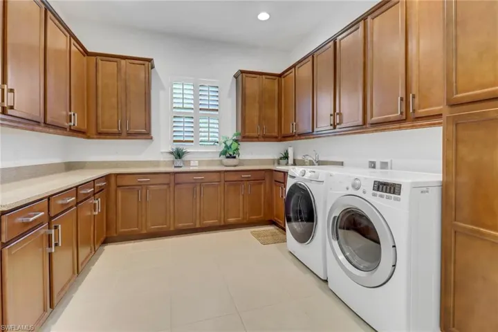 Oversized laundry room with tile floor, window and plenty of cabinets.
