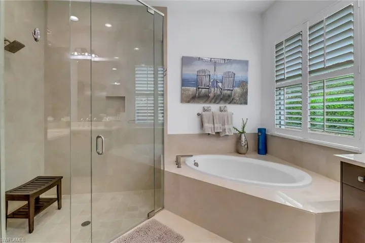 View of large shower with bench and large soaking tub.