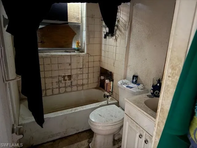 Bathroom with vanity, toilet, and a textured wall
