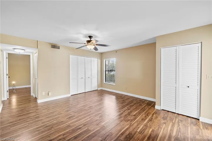 Unfurnished bedroom featuring two closets, wood finished floors, and a ceiling fan