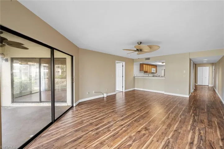 Unfurnished living room featuring a ceiling fan and dark wood-type flooring