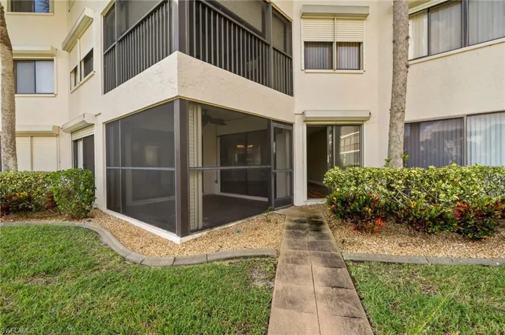 Property entrance featuring stucco siding, a sunroom, and a lawn
