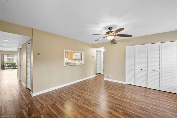 Unfurnished living room featuring dark wood-type flooring and ceiling fan