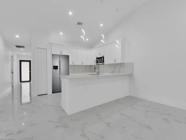 Kitchen with appliances with stainless steel finishes, recessed lighting, light countertops, a peninsula, and white cabinets