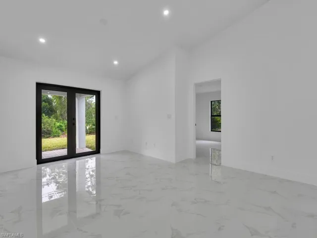 Spare room featuring plenty of natural light, recessed lighting, baseboards, light marble finish flooring, and vaulted ceiling