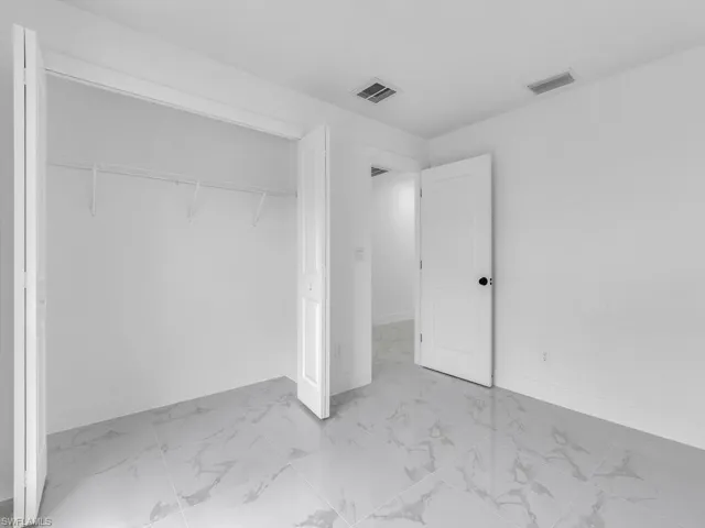 Unfurnished bedroom with marble finish flooring, baseboards, and a closet