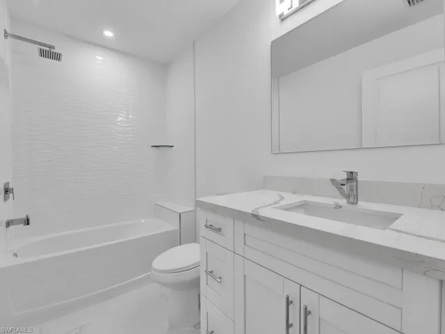 Bathroom featuring marble finish floors, toilet, bathing tub / shower combination, vanity, and recessed lighting