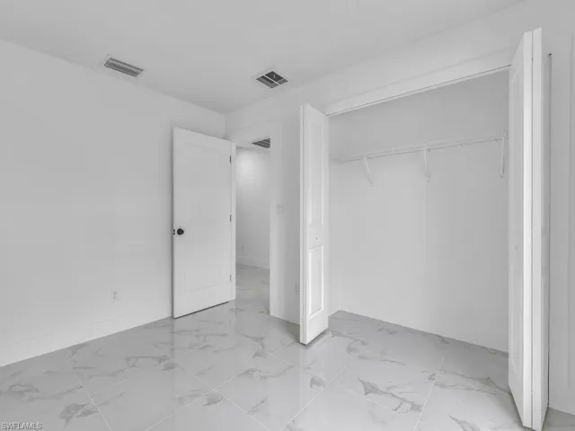 Unfurnished bedroom featuring marble finish floors, baseboards, and a closet