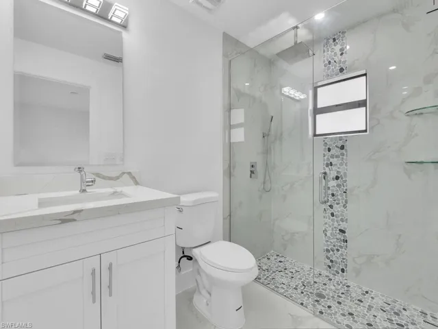 Full bath featuring toilet, a marble finish shower, vanity, and marble finish flooring
