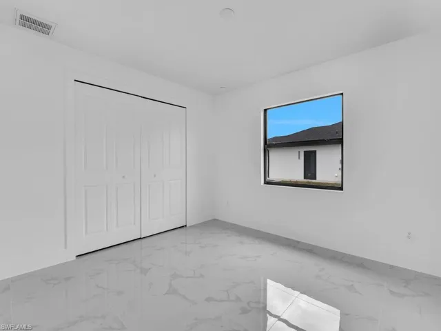 Unfurnished bedroom with light marble finish floors, a closet, and baseboards