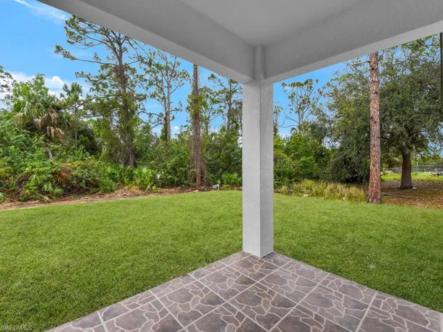 View of grassy yard with a patio and view of scattered trees