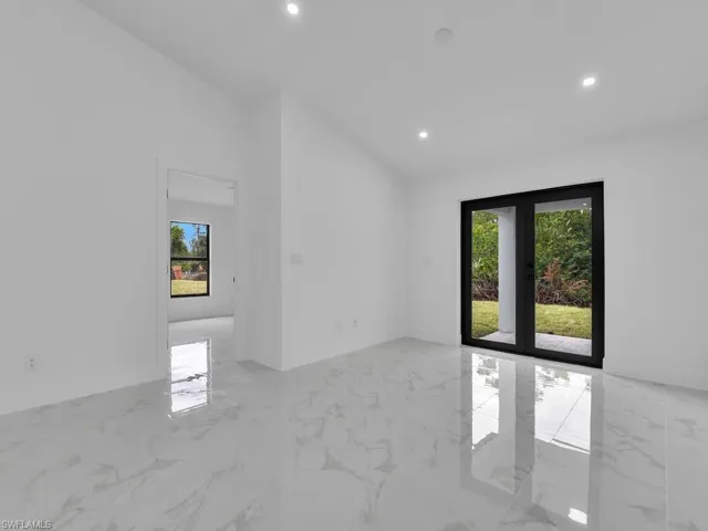 Unfurnished room with recessed lighting, marble tiled flooring, baseboards, and lofted ceiling