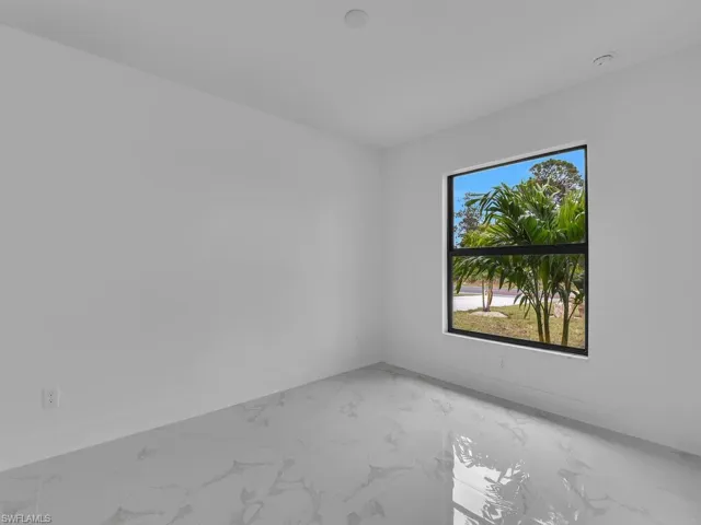 Spare room featuring light marble finish flooring and baseboards