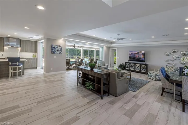 Living room featuring ceiling fan, a raised ceiling, light hardwood / wood-style flooring, and crown molding