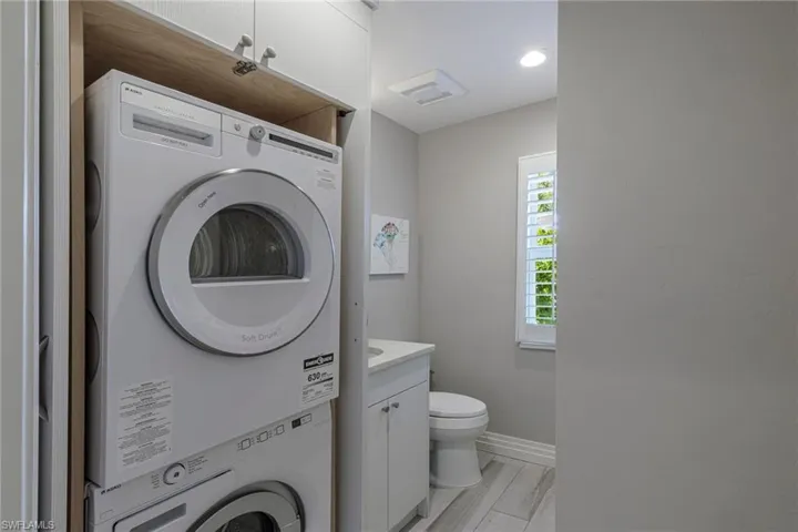 Laundry room featuring light hardwood / wood-style floors and stacked washer and dryer