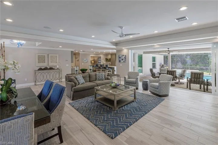 Living room with ceiling fan, light hardwood / wood-style flooring, and crown molding