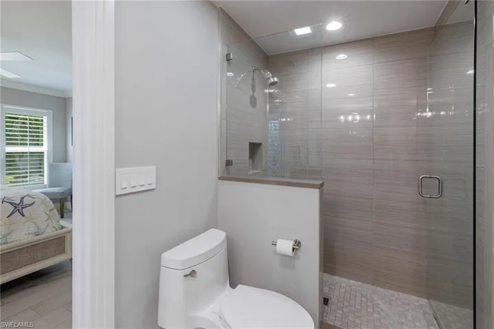 Bathroom featuring walk in shower, ornamental molding, and toilet