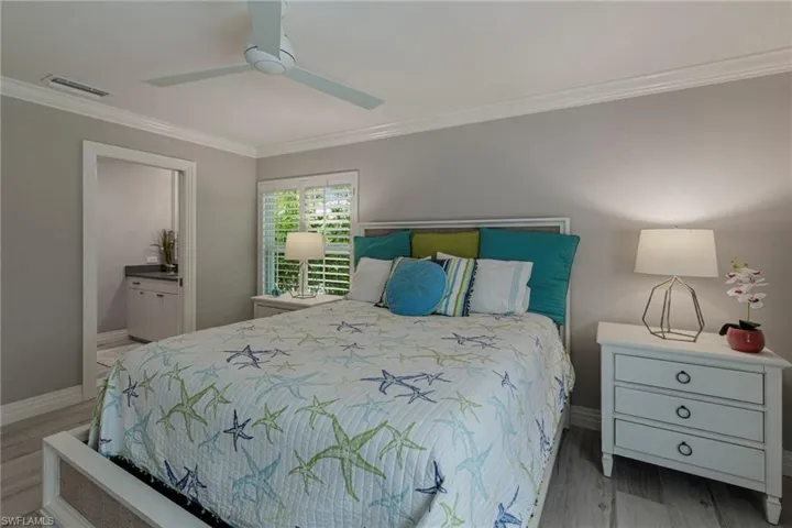 Bedroom with ceiling fan, ornamental molding, connected bathroom, and hardwood / wood-style flooring