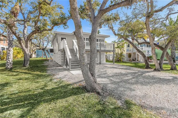 View of front of property with driveway, a wooden deck, stairs, a front lawn, and a carport