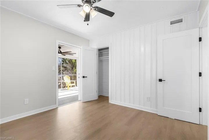 Unfurnished bedroom featuring wood finished floors, a ceiling fan, access to outside, and a closet