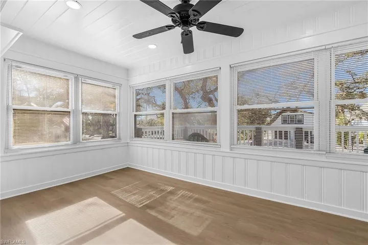 Unfurnished sunroom featuring wood finished floors, a decorative wall, wainscoting, and recessed lighting