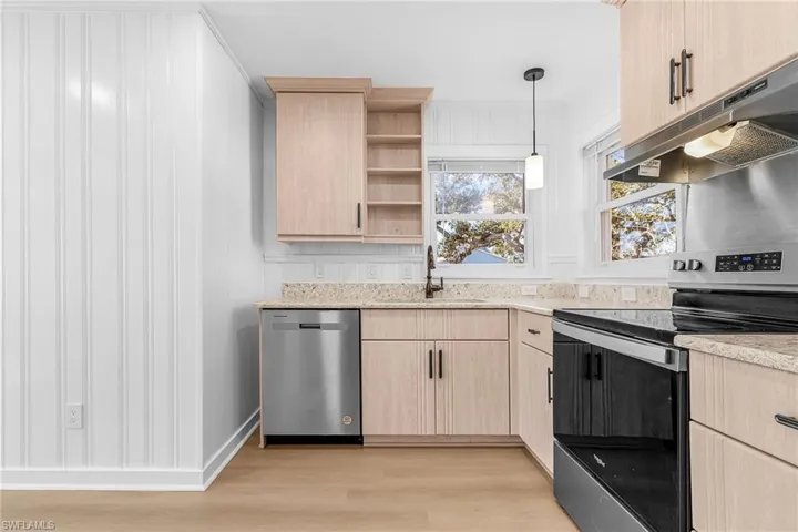 Kitchen featuring light brown cabinets, appliances with stainless steel finishes, pendant lighting, light wood-style flooring, and open shelves