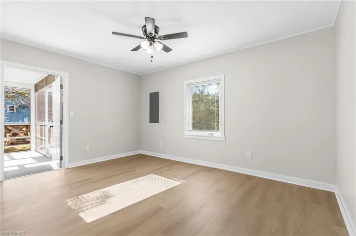 Empty room with light wood-style floors, electric panel, a ceiling fan, and crown molding