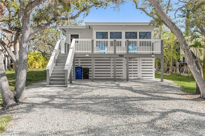 View of front of property with a wooden deck, gravel driveway, stairway, and an attached garage