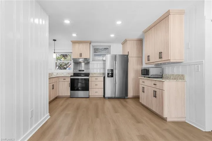 Kitchen featuring light brown cabinets, light stone countertops, appliances with stainless steel finishes, light wood-style floors, and recessed lighting