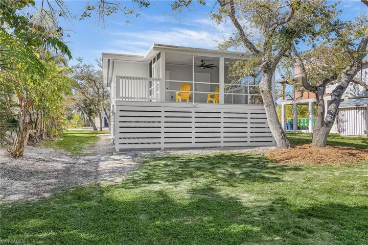 Rear view of property with ceiling fan, a sunroom, and a lawn