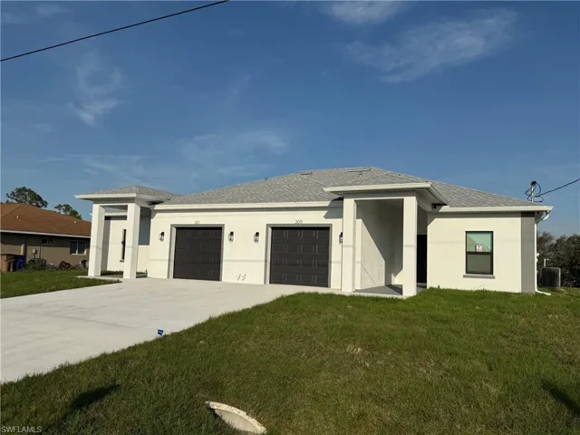 Prairie-style house featuring a garage, driveway, a front lawn, and stucco siding
