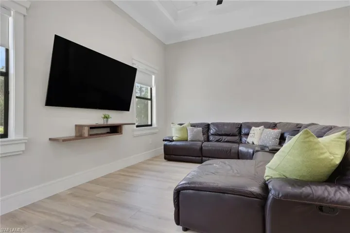 Living area featuring light wood-type flooring and a raised ceiling