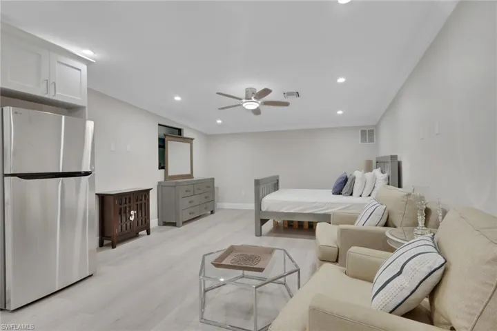 Bedroom featuring freestanding refrigerator, ornamental molding, light wood-style floors, a ceiling fan, and recessed lighting