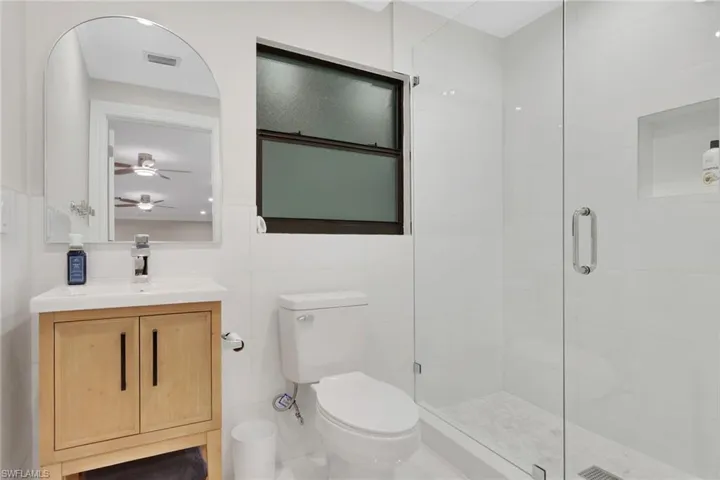 Bathroom with vanity, a stall shower, and tile walls