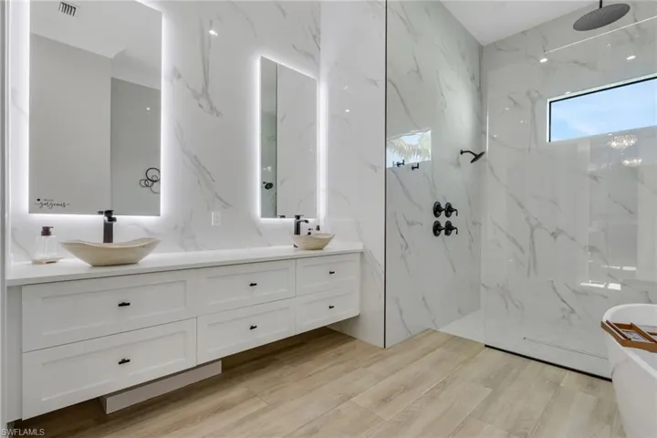 Bathroom featuring a marble finish shower, a freestanding bath, and double vanity