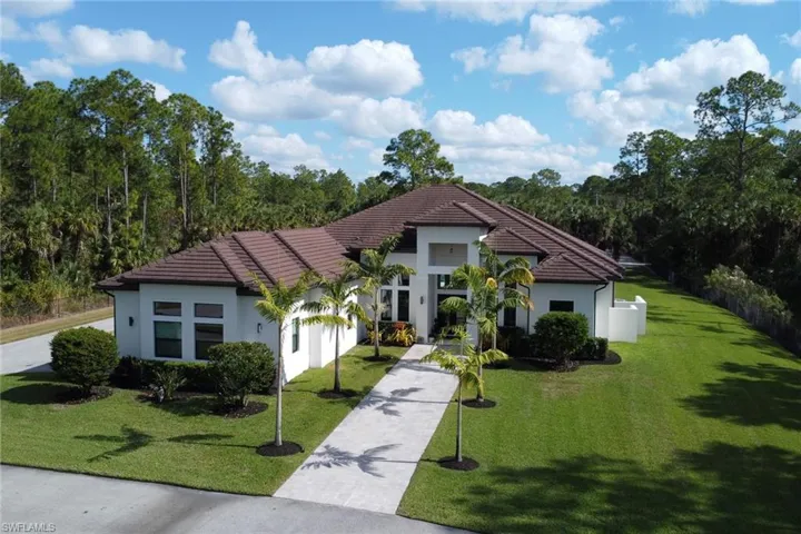 View of front of house with a front lawn, stucco siding, a tile roof, and driveway